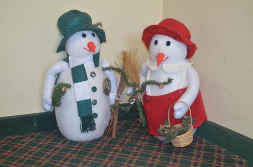 two fake snowmen are standing next to a wall at Santa's Lodge in Santa Claus