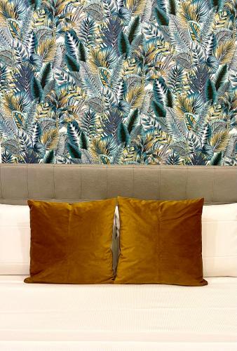 a bed with a yellow pillow and a wallpaper at Domus Cuseni in Taormina