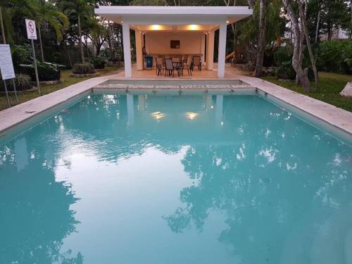 a swimming pool with blue water in front of a house at La Casa del Arbol -4bed 3 bath in Puerto Morelos