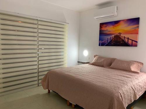 ein Schlafzimmer mit einem Bett und einem Gemälde an der Wand in der Unterkunft La Casa del Arbol -4bed 3 bath in Puerto Morelos