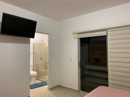 a bedroom with a bathroom with a television on the wall at La Casa del Arbol -4bed 3 bath in Puerto Morelos