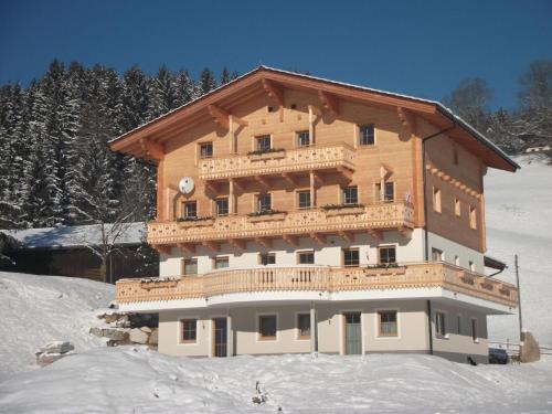 un gran edificio de madera en la nieve en Neue Ferienwohnung in Mittersill mit Grill und Garten en Hollersbach im Pinzgau