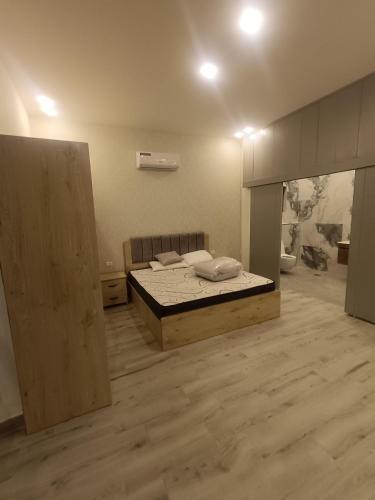 um quarto com uma cama e piso em madeira em Villa rotana airport road em Al Qasţal
