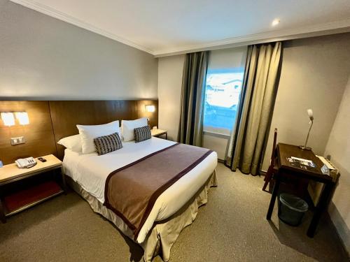 een hotelkamer met een groot bed en een raam bij Hotel Martín Gusinde in Puerto Natales