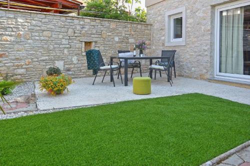 a patio with a table and chairs and grass at Ferienhaus für 6 Personen ca 86 qm in Peroj, Istrien Istrische Riviera in Peroj