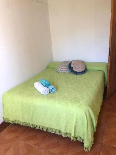 Una pequeña cama verde con toallas encima. en Amigo8 en La Punta