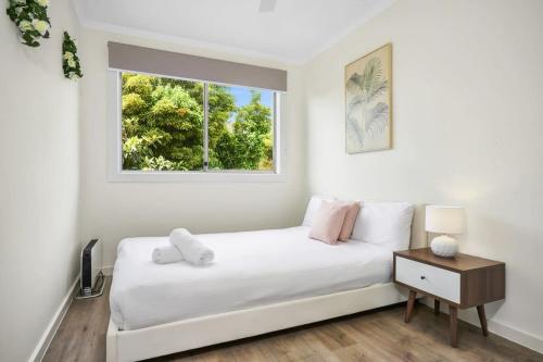 a white bedroom with a bed and a window at Modern Beach House - Dromana in Mornington