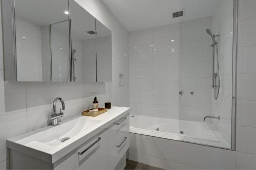 La salle de bains blanche est pourvue d'une baignoire, d'un lavabo et d'une douche. dans l'établissement Camberwell Serviced Apartments, à Melbourne