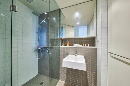 a bathroom with a sink and a glass shower at Docklands Convenient & Modern 1 Bed Apartment in Melbourne