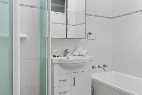 a white bathroom with a sink and a shower at Light filled Villa- Moments to the Beach in Blue Bay 