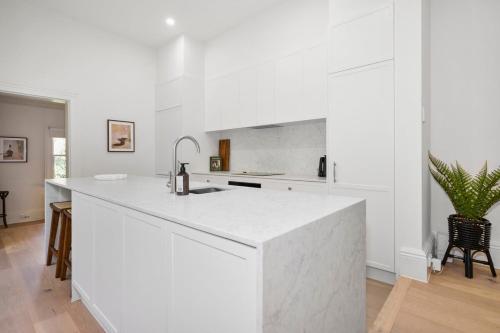 una cocina blanca con una gran encimera blanca en Cozy North Melbourne Family Retreat, en Melbourne
