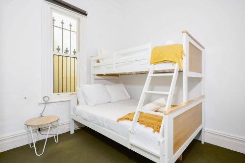 a white bunk bed in a white room with a ladder at Yarraville - Modern Historic Home in Yarraville