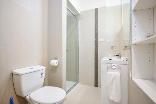 a white bathroom with a toilet and a shower at Yarraville - Modern Historic Home in Yarraville
