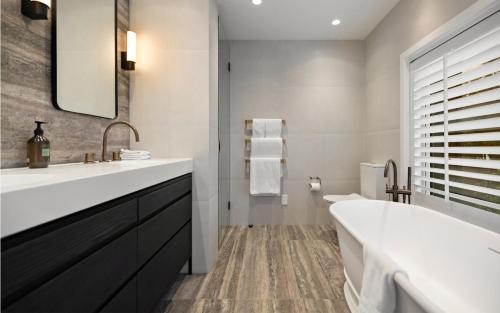 een badkamer met een grote wastafel en een bad bij Aroha Homestead Luxury Holiday Home by MajorDomo in Frankton