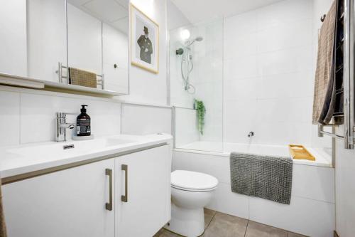 a white bathroom with a toilet and a sink at 2BR Penthouse Apt Rooftop Terrace, Spa & BBQ in Melbourne