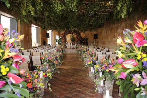 une chambre remplie de chaises et de fleurs dans des vases dans l'établissement Hotel Hicasua y Centro de Convenciones, à Barichara
