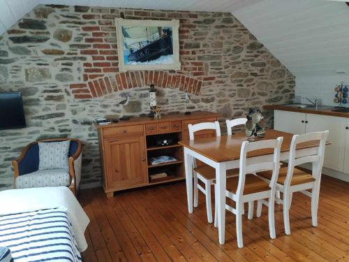 une cuisine avec une table et des chaises et un mur en pierre dans l'établissement studio Marie, à Cancale