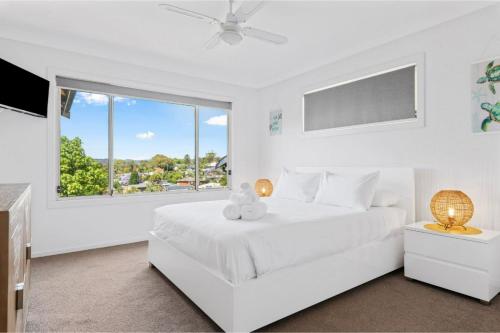 Un dormitorio blanco con una cama blanca y una ventana en Holiday Home with Ocean Views Wamberal, en Wamberal