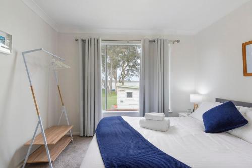a bedroom with a bed and a large window at Lake Front Home - Relax & Unwind in Budgewoi