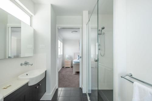 een witte badkamer met een wastafel en een douche bij Spacious And Luxurious Beach Home in Catherine Hill Bay