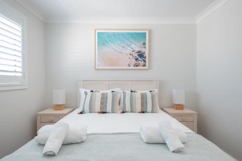 een witte slaapkamer met een bed met 2 nachtkastjes bij Spacious And Luxurious Beach Home in Catherine Hill Bay
