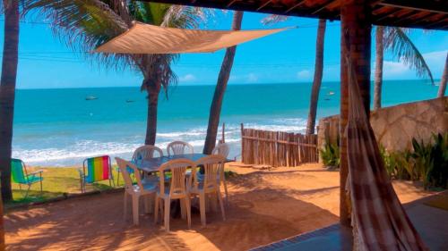 uma mesa e cadeiras numa praia com o oceano em Casa da Peroba Sol em Icapuí