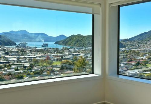 a room with two windows with a view of a city at Picton Hilltop Apartment in Picton