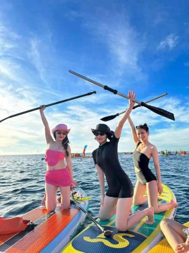 three women on a paddle board in the water at White's house in Quan Lạn