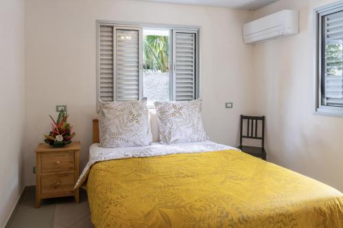 um quarto com uma cama com um edredão amarelo e 2 janelas em PARADISE em Bora Bora