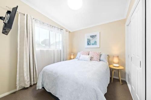 een slaapkamer met een wit bed en een raam bij Crepe Myrtle Lodge in Blackwall