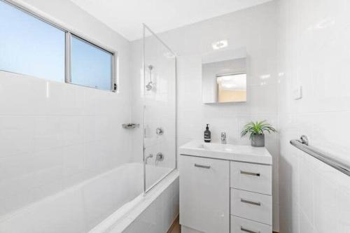 een witte badkamer met een douche en een wastafel bij Crepe Myrtle Lodge in Blackwall