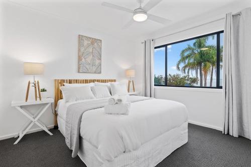 a white bedroom with two beds and a large window at Waterfront Luxury Living & Private Pool Buff Point in Budgewoi