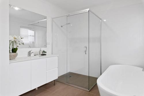 a white bathroom with a shower and a sink at Waterfront Luxury Living & Private Pool Buff Point in Budgewoi