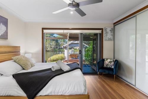 a bedroom with a bed and a sliding glass door at Riverfront- Heated Pool, Sauna, Kayaks in Chittaway Point