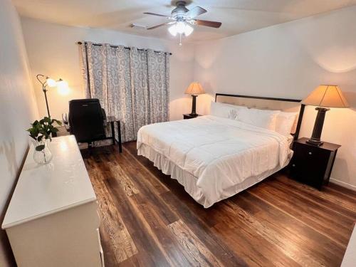 a bedroom with a white bed and wooden floors at The Wisteria in Humble