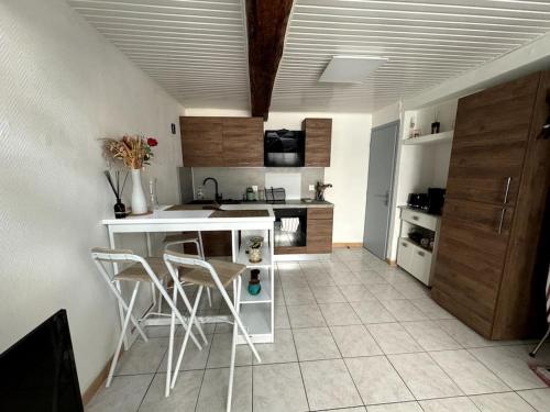 - une cuisine avec un comptoir blanc et des chaises dans l'établissement Duplex au coeur du Boulou, au Boulou