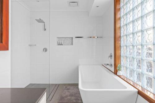 een witte badkamer met een toilet en een douche bij Ultimate Lakefront Luxury, Pool Table, Games Room in Berkeley Vale