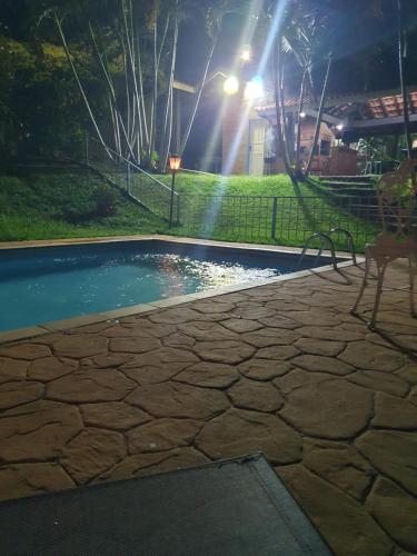 una piscina por la noche con un banco y una luz en Casa de Campo em Itatiba, en Itatiba