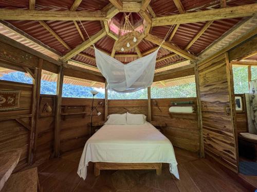 a bedroom with a bed in a wooden cabin at Cabaña Guasale (Toucan) in Guachaca