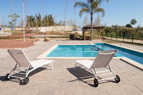 dwa krzesła siedzące przed basenem w obiekcie Depa Ye w mieście El Alcanfor