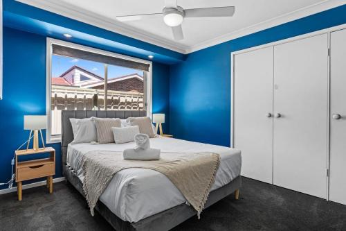 a blue bedroom with a bed and a window at Serene Family Paradise in Pelican Flat
