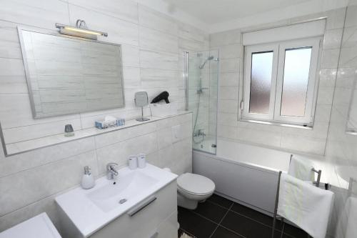La salle de bains blanche est pourvue d'un lavabo et de toilettes. dans l'établissement Apartments with a swimming pool Stobrec, Split - 22897, à Podstrana