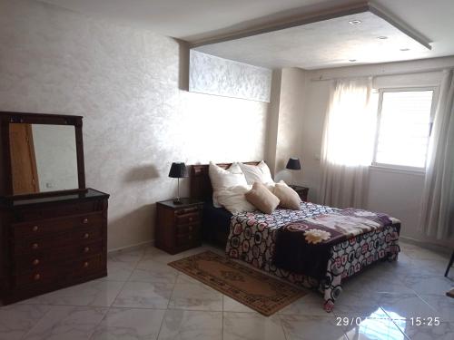 Schlafzimmer mit einem Bett, einer Kommode und einem Spiegel in der Unterkunft Appartement proche de toutes les commodités, RESIDENCE MARWA in Oulad Yakoub