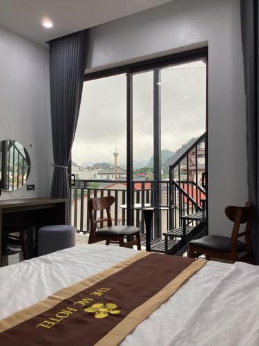 a bedroom with a bed and a balcony with a view at The MC hotel mộc châu in Mộc Châu