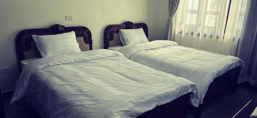 2 camas en una habitación con sábanas y almohadas blancas en White House - Nhà khách Báo nhân dân TAM ĐẢO, en Vĩnh Phúc