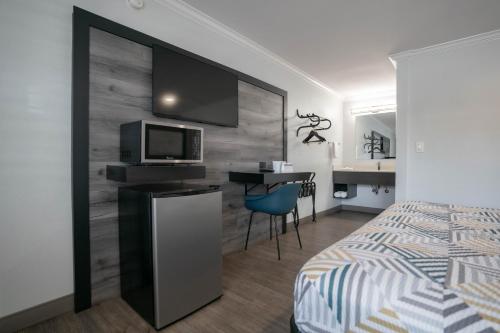 a bedroom with a bed and a desk with a tv at Motel 6 Pico Rivera - Los Angeles, CA in Pico Rivera