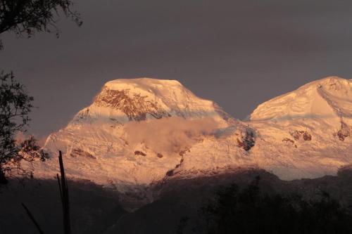 two snow covered mountains with the sun shining on them at Almawasi Lodge in Yungay