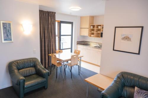 a living room with a table and chairs and a kitchen at Victoria Court Motor Lodge - Free Parking in Wellington