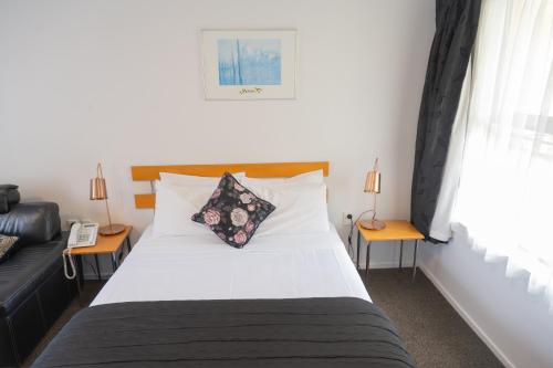 a bedroom with a white bed with two tables and a phone at Victoria Court Motor Lodge - Free Parking in Wellington