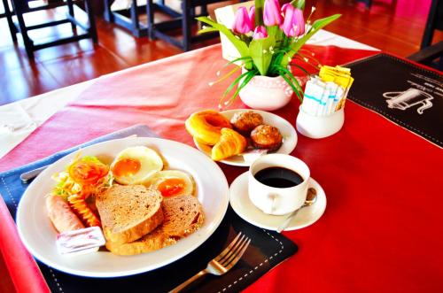 a table with two plates of breakfast foods and a cup of coffee at Sayang Beach Resort Koh Lanta in Ko Lanta